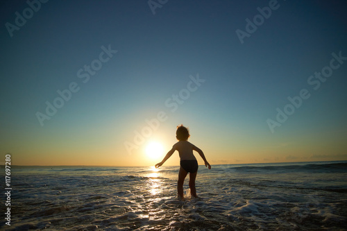 boy playing on the beach at sunset © photoniko