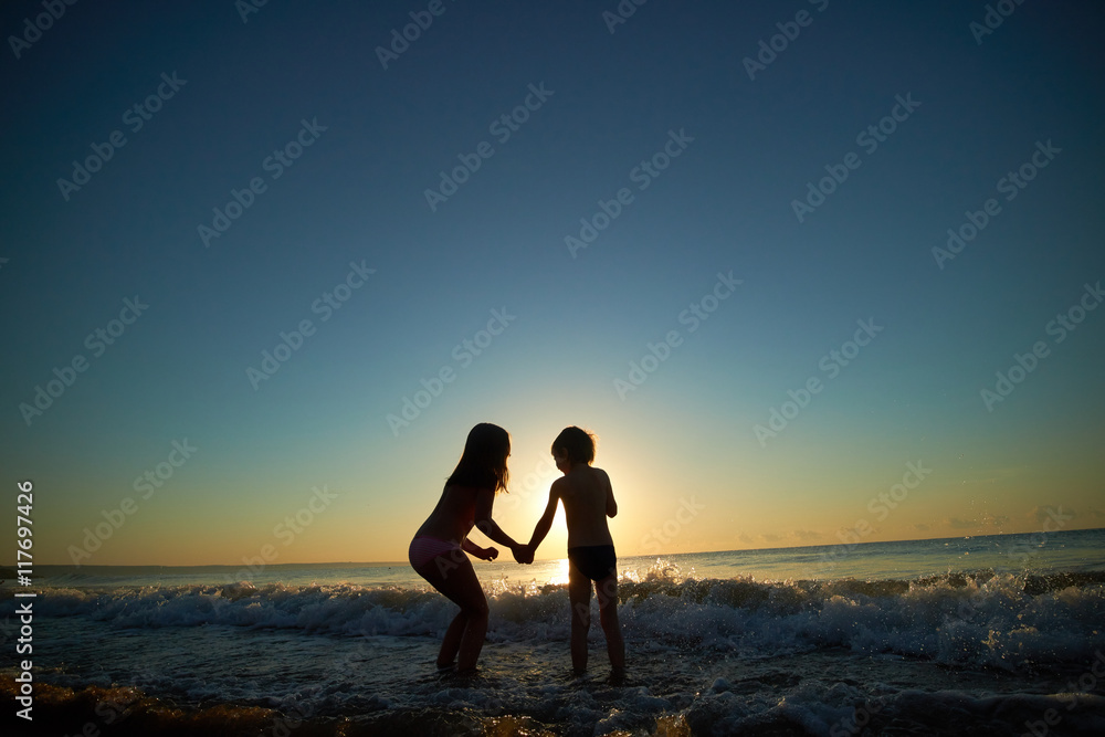 boy and girl on the sea at sunset