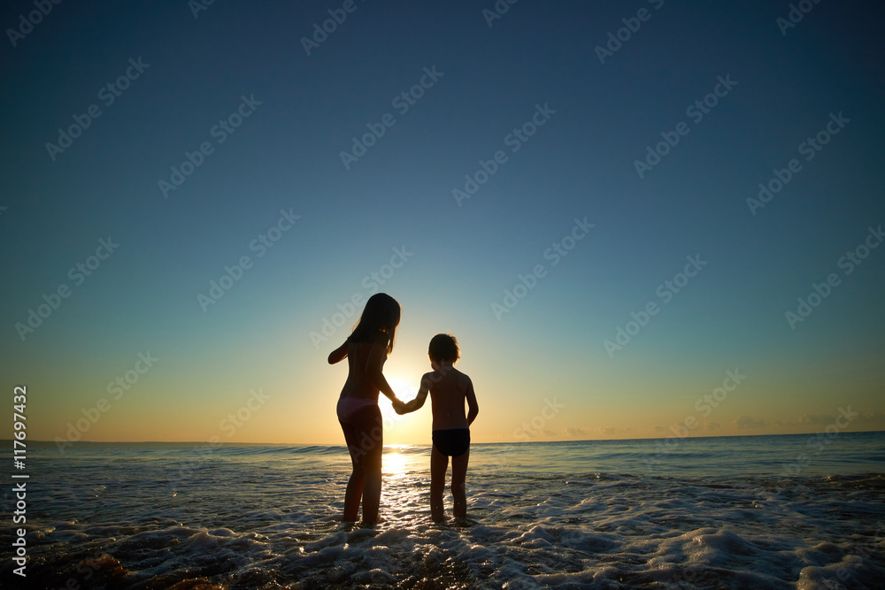 boy and girl on the sea at sunset