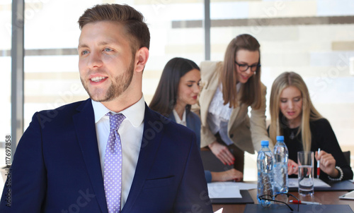 Happy smart business man with team mates discussing in the background