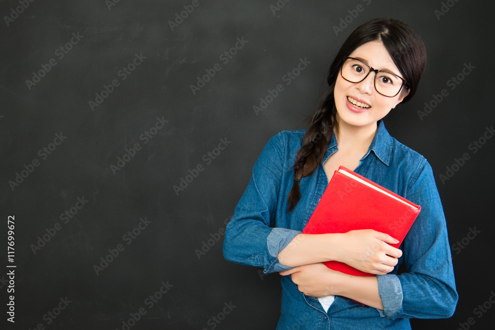 smiling student holding textbook at blackboard before the class smiling student holding textbook at blackboard before the class