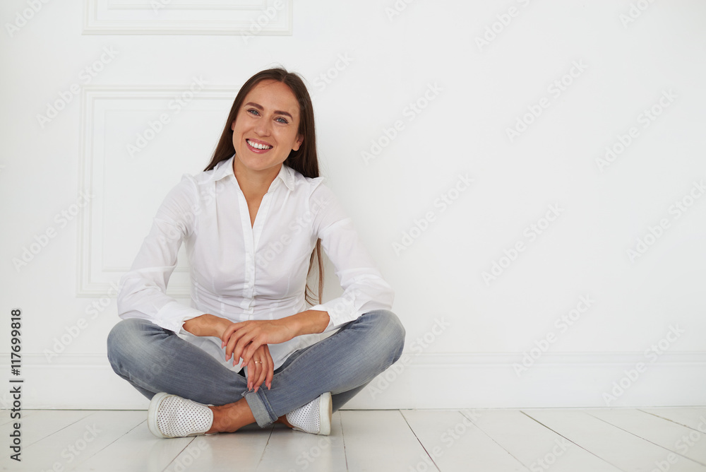 Happy pleased young smiling woman is sitting on the floor Happy pleased young smiling woman is sitting on the floor
