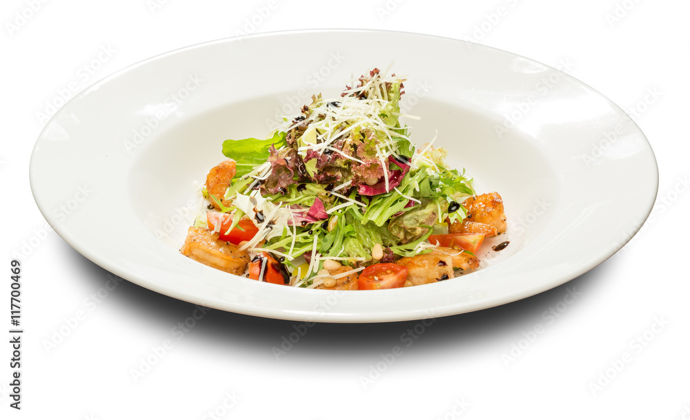 Salad with shrimp and arugula decorated with pine orehami.Na white plate and a white background