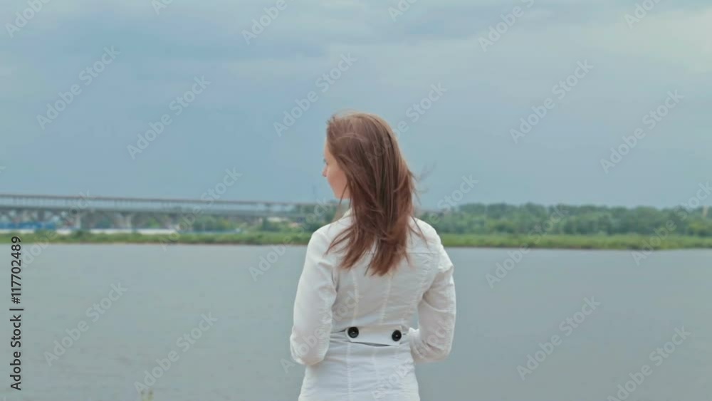 Young woman in embankment, hair blowing in wind