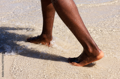 African man feet walking on the beach