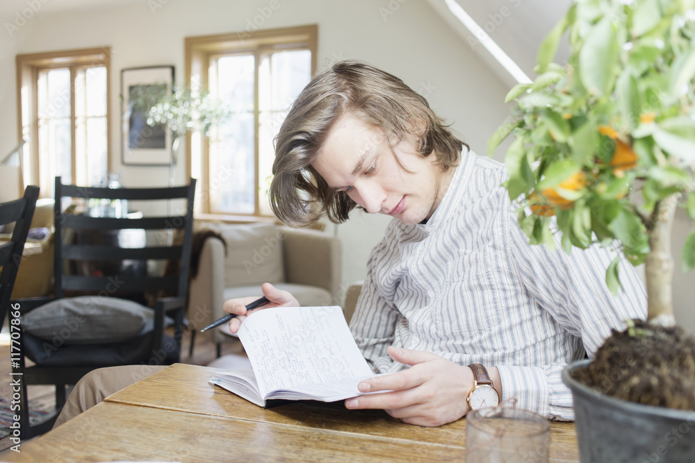 Young man reading notes from book at table in restaurant Young man reading notes from book at table in restaurant