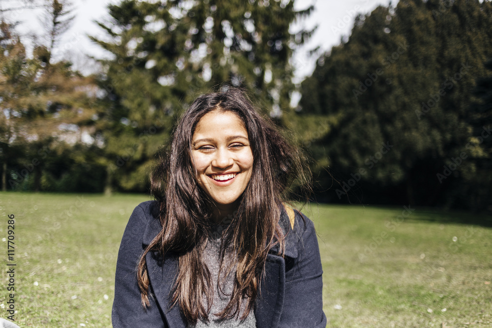Portrait of happy young woman sitting in park Portrait of happy young woman sitting in park