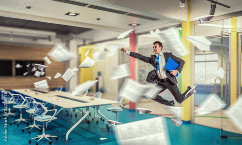 Jumping businessman in office . Mixed media