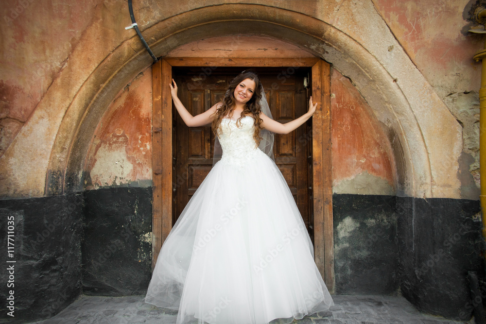 Bride stands in the wooden entrance to the old building