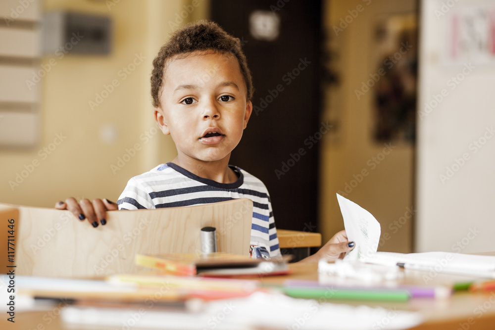 Boy Using Paper Portrait of cute boy holding drawing paper in classroom Stock Photo ...