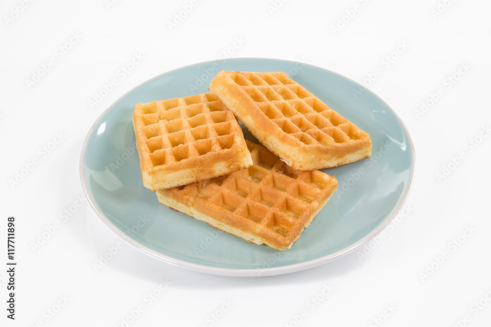Drei eckige Waffeln liegen auf einem blauen Teller. Hintergrund weiss. Drei eckige Waffeln liegen auf einem blauen Teller. Hintergrund weiss.