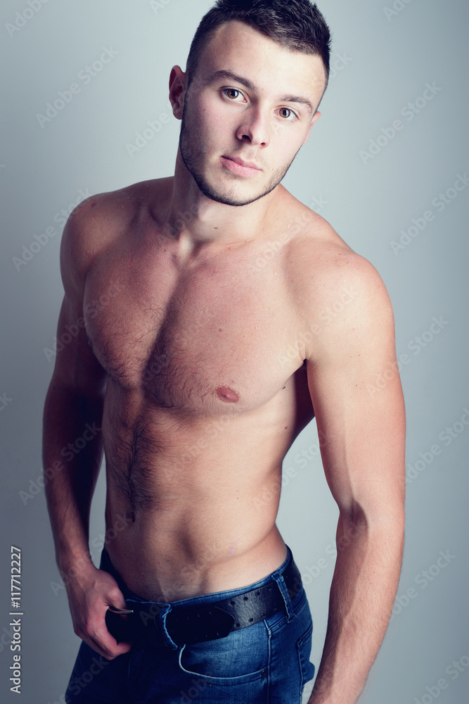 Young handsome guy posing in a studio with a beautiful body