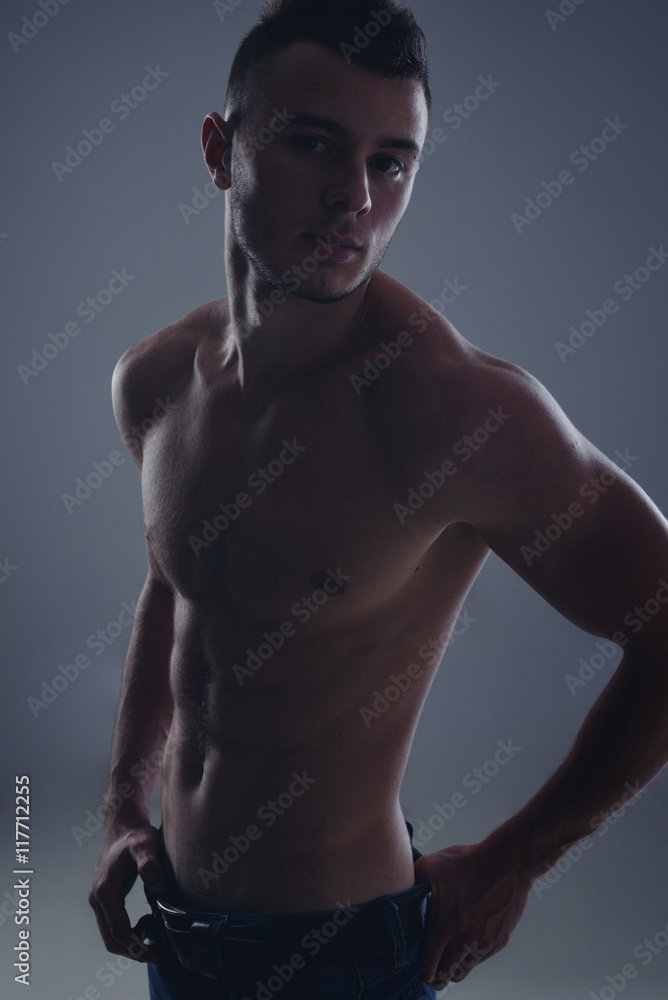 Young handsome guy posing in a studio with a beautiful body
