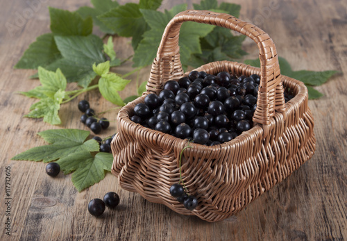 Black currants in a basket on the old wooden table