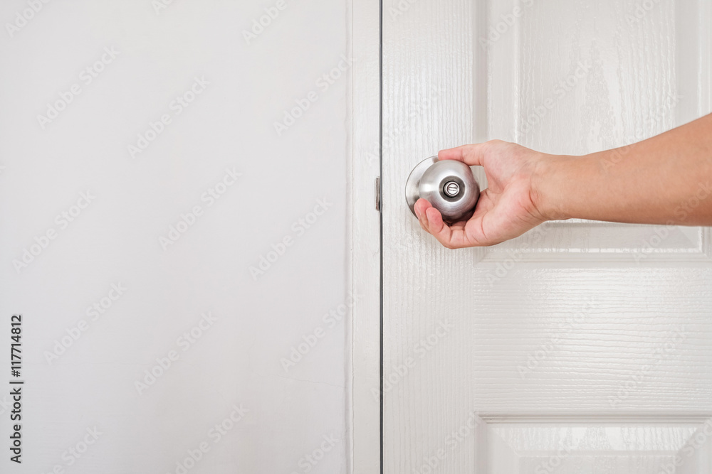 Naklejka premium Hand holding door knob, white door and wall, with copy space