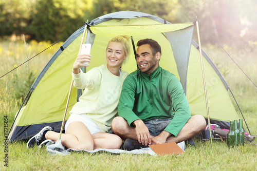 Couple camping in forest and taking selfie