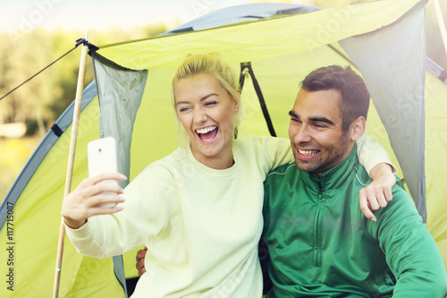 Couple camping in forest and taking selfie