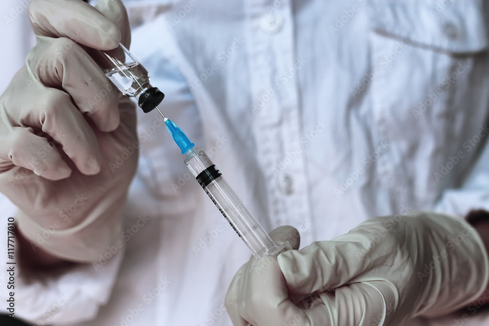 health worker dials the vaccine into a syringe health worker dials the vaccine into a syringe