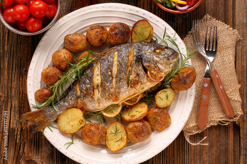 Photography Grilled fish with roasted potatoes and vegetables on the plate