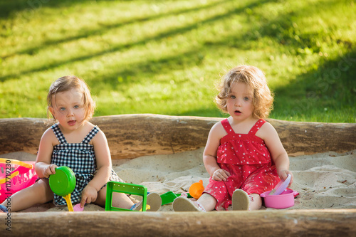 Fototapeta The two little baby girls playing toys in sand