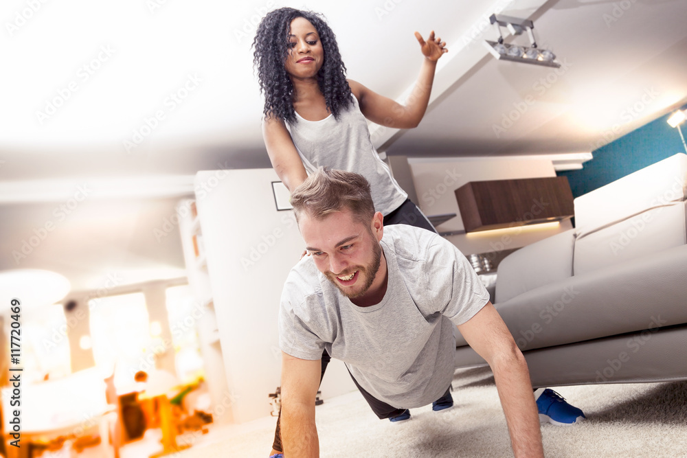 Obraz premium young couple having fun doing gymnastics at home