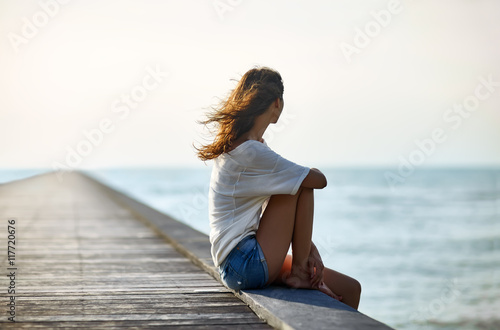 Photos Young beautiful woman sitting on the pier