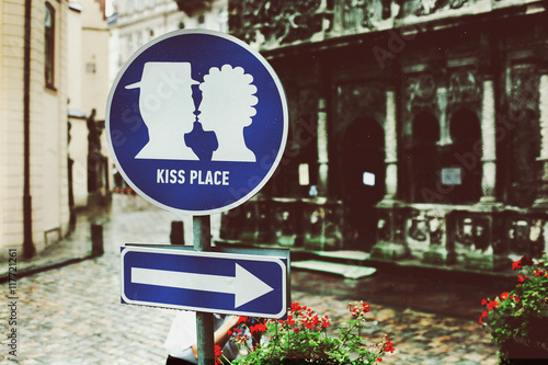 A road marker 'Kiss place' stands on the old city square