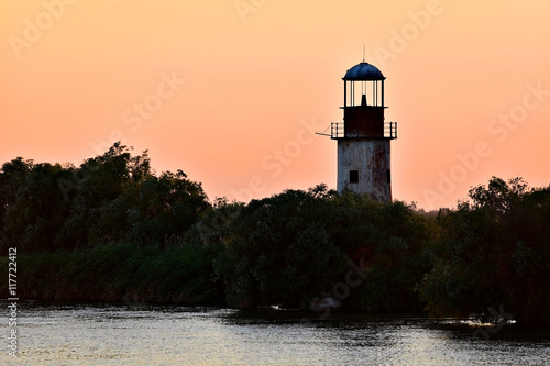 Abandoned lighthouse at sunset on a river