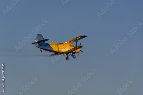 Crop duster spraying crops from the air in the morning light while turning to make another spraying run.