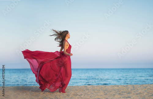 Tableau sur toile Girl in airy dress running along the beach