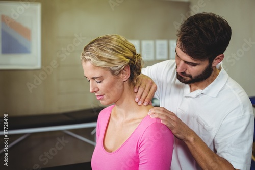 Male physiotherapist giving neck massage to female patient