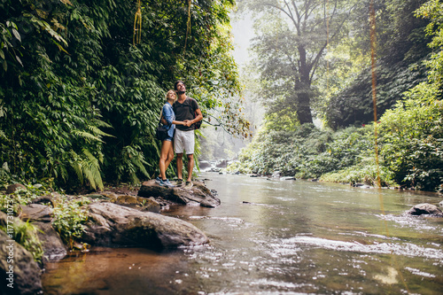 Young couple together by the creek and looking away