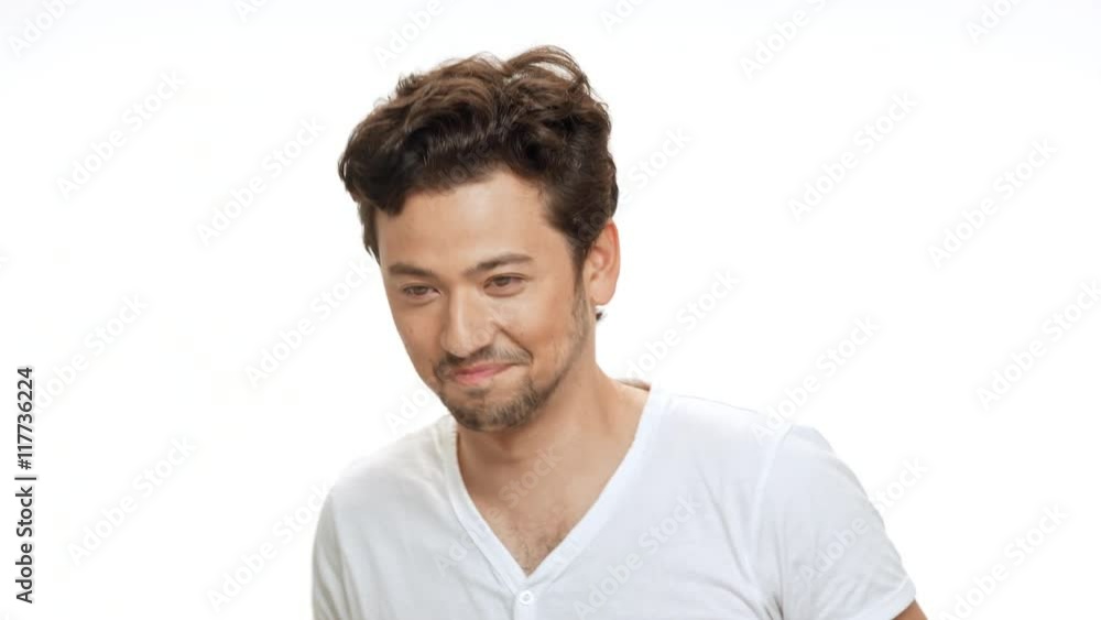 Shy young handsome man smiling, looking at camera over white background. Shy young handsome man smiling, looking at camera over white background.