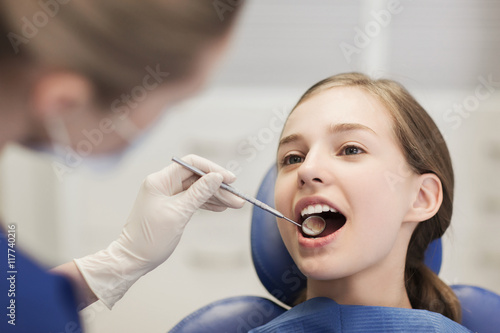 female dentist checking patient girl teeth