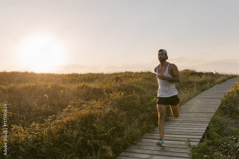 Spain, Aviles, athlete man running along a coastal path at sunset Spain, Aviles, athlete man running along a coastal path at sunset