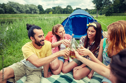 happy friends with tent and drinks at campsite © Syda Productions