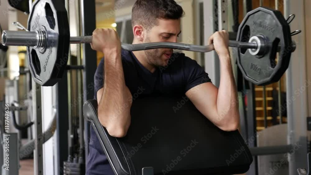 Young man in the gym, exercise for the biceps Young man in the gym, exercise for the biceps