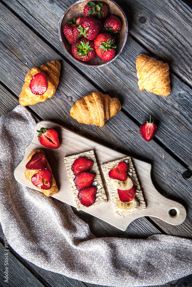 A delicious breakfast of strawberries and bread on wooden backgr