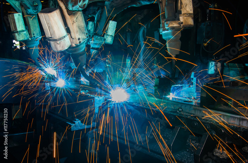 Robots welding metal in factory