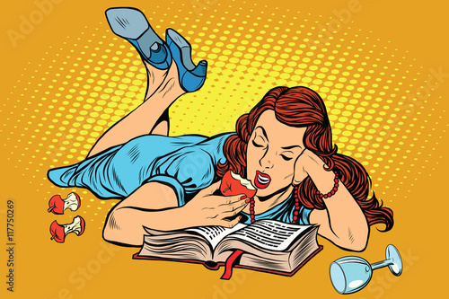 Beautiful woman lying down reading a book and eating an Apple