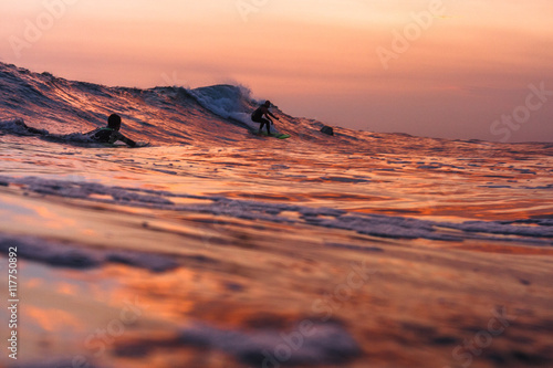 A surfer riding a wave at sunset 