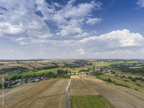 Aerial view of the blue sky and village harvest fields at summer