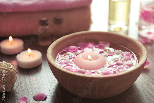 Petals in bowl with candles on wooden background