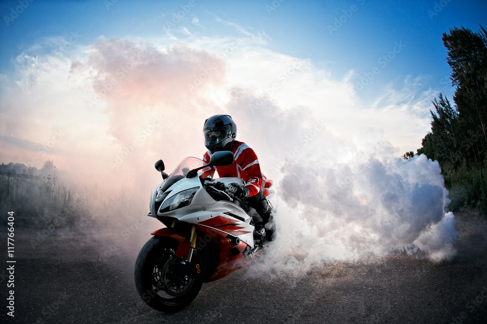 biker staying on bike road with smoke of the tire, burn out in the moto  show. the Sunset Stock Photo | Adobe Stock