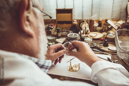 Rear view of horologist repairing a watch photo
