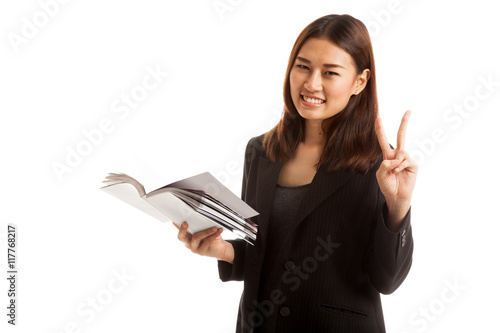 Young Asian business woman show victor sign with a book.