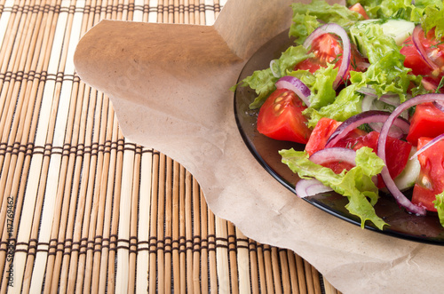 Closeup view on a plate with fresh salad of raw tomatoes, lettuc photo