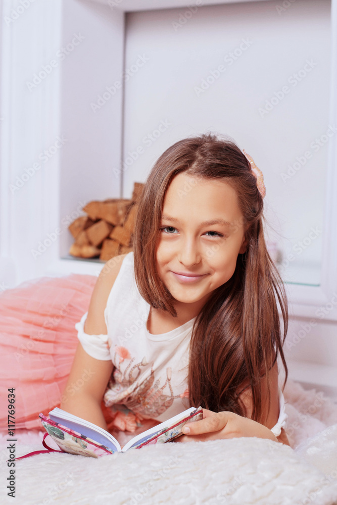 cute girl lying on soft fur and reading a book