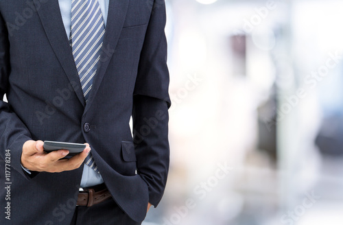 isolated business man hold the smartphone on shopping mall background