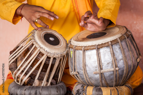 A young boy playing on traditional Indian tabla drums. 